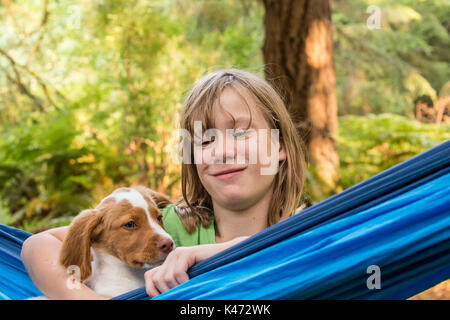 Dieci anni di vecchia ragazza guardando i suoi due mese vecchio Epagneul Breton "Archie" che è appoggiato in una amaca, Issaquah, Washington, Stati Uniti d'America Foto Stock
