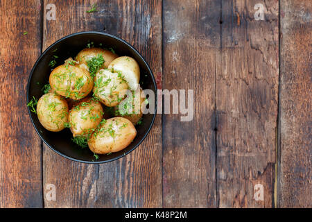 Giovani bollita con patate aneto e burro su una tavola di legno, vista dall'alto, closeup. Stile rustico Foto Stock