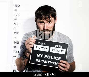 Uomo Barbuto in manette detiene un segno, Penale mug shots Foto Stock