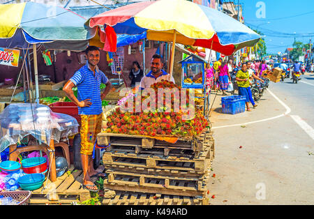 Wellawaya, sri lanka - 2 dicembre 2016: il mercato di venditori offrono maturi frutti tropicali rambutans, il 2 dicembre in wellawaya Foto Stock