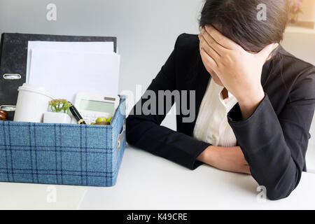 Tristezza bella femmina lavoratore di ufficio è sparato imballaggio oggetti personali seduto sulla scrivania sensazione sconvolto e pensare in futuro posto di lavoro Foto Stock