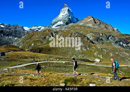 Tre turisti nell'area escursionistica attorno a Zermatt, il Lago Schwarzsee e Cervino dietro, Zermatt, Vallese, Svizzera Foto Stock