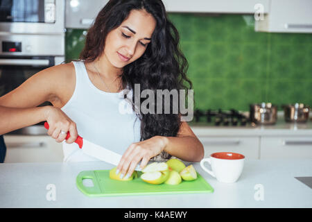 Donna taglia verdure insieme in cucina Foto Stock