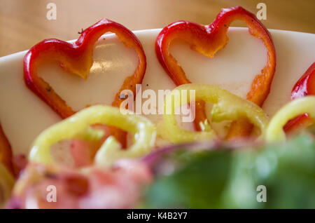 Le insalate e a forma di cuore i peperoni su una tavola di legno Foto Stock