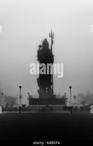 Foto in bianco e nero,girato in un giorno di nebbia per creare una sensazione di mistico, straordinaria statua del signore Shiva (Mangal Mahadev) a Grand Bassin in Mauritius. Foto Stock
