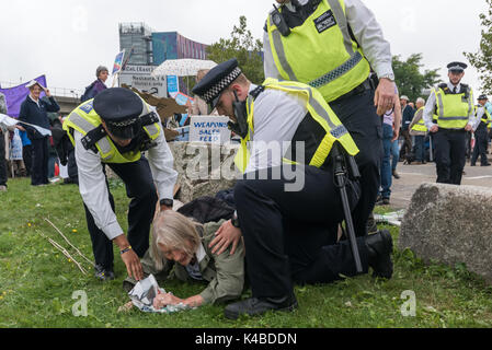 Londra, Regno Unito. 5 Sep, 2017. La polizia abbassare delicatamente un Quaker protester hanno portato fuori strada sull'erba nel secondo giorno di proteste contro il mondo la più grande fiera di armi detenute nelle Docklands di Londra. Il 'Nessuna fede nella guerra' giorno era una serie di eventi organizzati da vari gruppi di fede. Prima del mio arrivo vi era stato un lock-in sull'approccio road arrestando le consegne provenienti per impostare il giusto attraverso la porta est. Credito: Peter Marshall / Alamy Live News Foto Stock