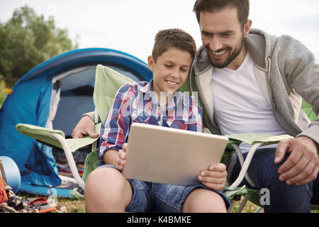 Padre e figlio durante la navigazione in Internet sul campeggio Foto Stock