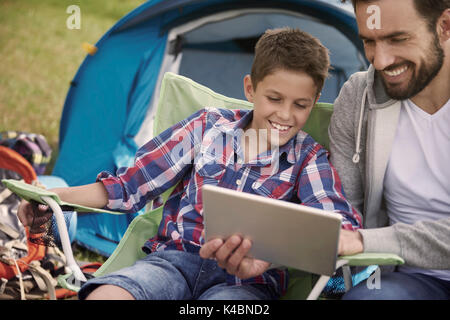 Padre e figlio durante la navigazione in Internet sul camping Foto Stock