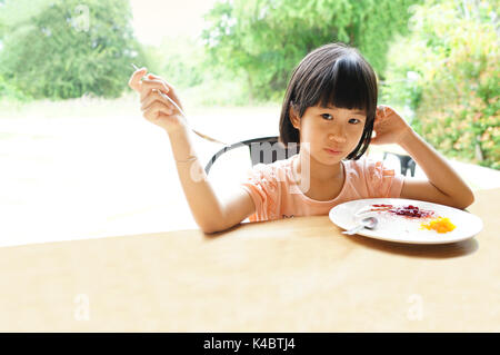 Ragazza asiatica 6s colazione pasto piastra sedersi nella tabella Foto Stock
