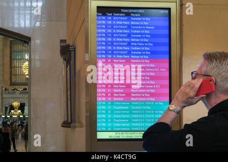 Uomo Senior controllo treno Partenze pensione in Grand Central Terminal, NYC, STATI UNITI D'AMERICA Foto Stock