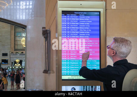 Uomo Senior controllo treno Partenze pensione in Grand Central Terminal, NYC, STATI UNITI D'AMERICA Foto Stock