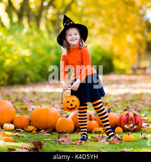 I bambini con la zucca di Halloween. Bambina in costume da strega e hat giocando in autunno park. Bambino di Halloween dolcetto o scherzetto. Kid trucco o trattare. Foto Stock