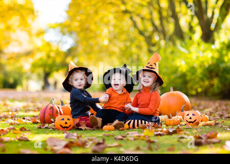 I bambini in nero e arancio strega costume e hat giocare con zucca e ragno in autunno park di Halloween. Kids dolcetto o scherzetto. Un ragazzo e una ragazza carving Foto Stock