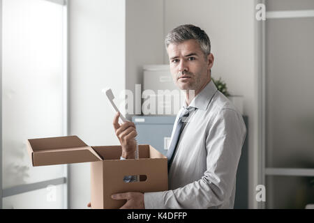 Scioccato lavoratore di ufficio riceve una chiamata a sorpresa all'interno di una scatola di cartone, stressante lavoro e stalking concept Foto Stock