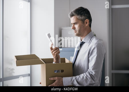 Scioccato lavoratore di ufficio riceve una chiamata a sorpresa all'interno di una scatola di cartone, stressante lavoro e stalking concept Foto Stock