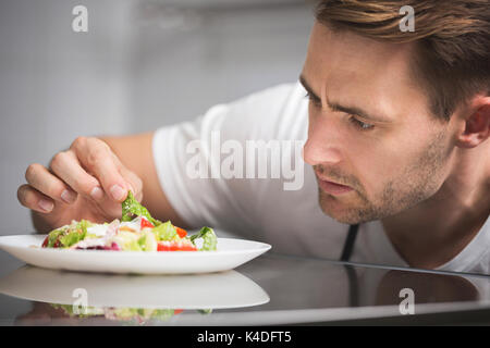 Close up ritratto maschile di chef insalata di preparazione Foto Stock