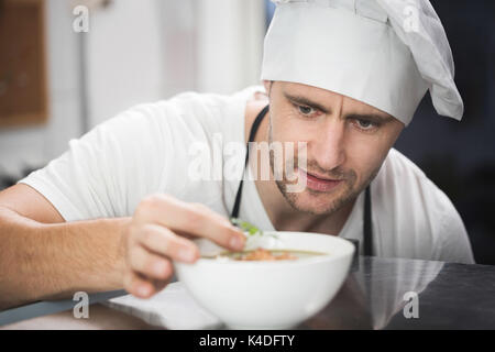 Close up front ritratto maschile di chef zuppa di farcitura Foto Stock