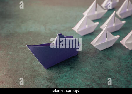 Carta Origami nave con piccole barche a vela, il concetto di leadership, tonificante Foto Stock