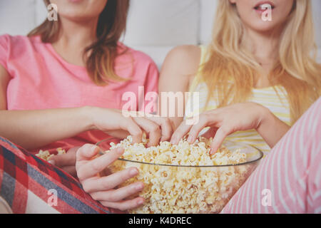 Ritagliato ritratto della ciotola di vetro di popcorn e due ragazze. Foto Stock