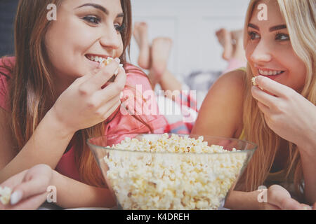 Close up ritratto di felice amici avente pigiama party mangiare popcorn. Foto Stock