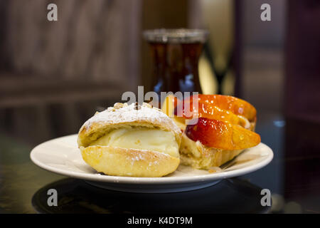 La pagnotta con crema pasticcera e zucchero in polvere. la torta di pesche in uno smalto. Foto Stock