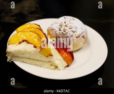 La pagnotta con crema pasticcera e zucchero in polvere. la torta di pesche in uno smalto. Foto Stock