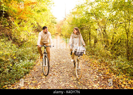 Coppia giovane in vestiti caldi in bicicletta nel parco d'autunno. Foto Stock