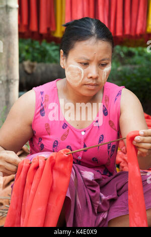 La banda di gomma fabbrica, Stato Mon, Myanmar. Tinti in lattice di gomma viene rimossa dai mandrini di legno prima di guillotining per creare le strisce di gomma Foto Stock