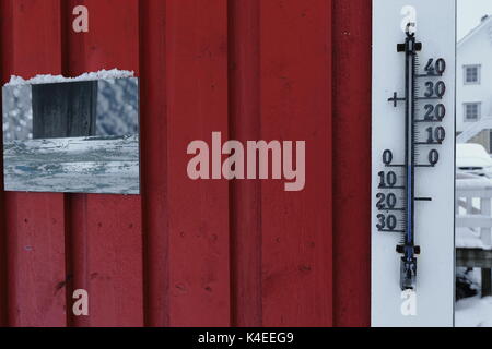 Termometro da parete che mostra zero gradi della temperatura sulla parete rossa o rorbu tradizionali di pesca stagionali hut-ora per uso turistico-una estremità su pali in Foto Stock