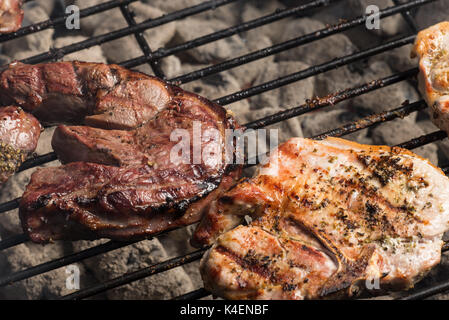 Condito costolette di maiale e bistecca di agnello per la cottura sul carbone di legna per barbecue grill. Foto Stock