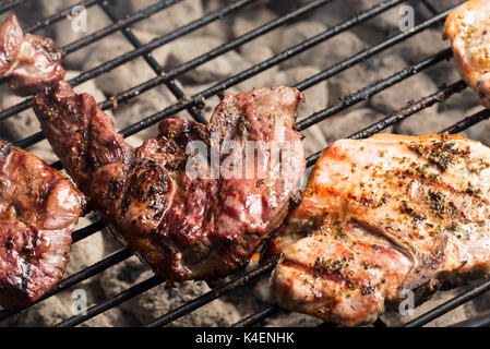 Condito costolette di maiale e bistecca di agnello per la cottura sul carbone di legna per barbecue grill. Foto Stock