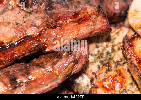 Close-up di agguerriti costolette di maiale e di agnello bistecca cotta su carbone di legna per barbecue grill. Foto Stock