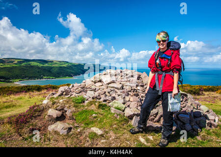 Giovani walker pone dalla pietra cairn sulla collina Bossington con Porlock Bay in background. Foto Stock