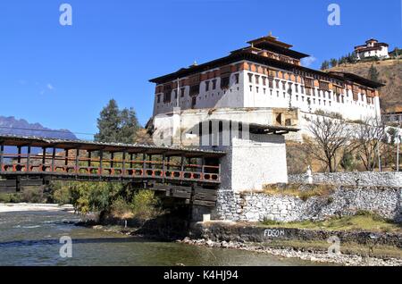 Paro Rinpung Dzong, il tradizionale Bhutan palace con il ponte di legno attraverso il fiume Paro Chu vicino alla città di Paro, Bhutan Foto Stock