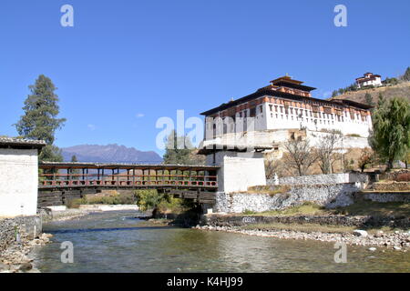 Paro Rinpung Dzong, il tradizionale Bhutan palace con il ponte di legno attraverso il fiume Paro Chu vicino alla città di Paro, Bhutan Foto Stock