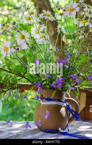 Brocca con un bouquet di fiori d'estate su un tavolo in giardino Foto Stock