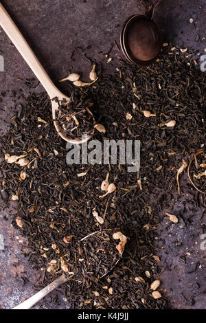 Tè nero sciolto con fiori di gelsomino su sfondo scuro Foto Stock