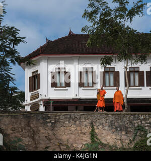 I monaci in piedi sulla parete di ritegno, Luang Prabang, Laos Foto Stock