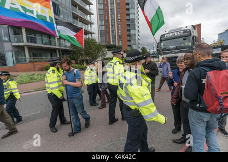 5 settembre 2017 - Londra, Regno Unito - Londra, Regno Unito. 5 settembre 2017. Forza di polizia della gente che cammina lentamente con le bandiere di fronte ad un camion che vanno verso il West Gate nel mondo la più grande fiera di armi detenute nelle Docklands di Londra fuori strada. Ciò era parte della 'Nessuna fede in guerra " giorno di proteste organizzate da diversi gruppi di fede. Prima del mio arrivo vi era stato un lock-in sull'approccio road arrestando le consegne provenienti per impostare il giusto attraverso la porta est. Questa è stata seguita da una riunione di Quaker a lato della strada durante la quale un certo numero di persone che stavano in piedi o seduto per bloccare la strada e diversi wh Foto Stock