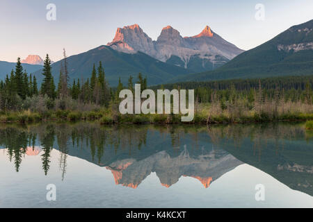 Le tre sorelle riflettendo in acque calme, Atmosfera mattutina, il fiume Bow, Canmore, il parco nazionale di Banff, Alberta, Canada Foto Stock