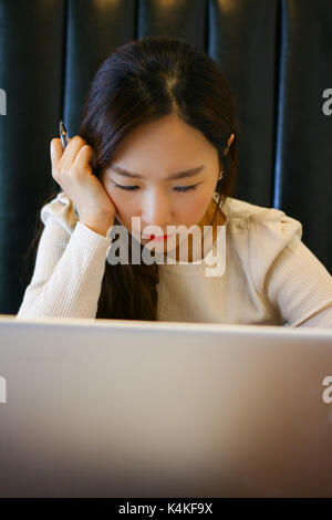 Ritratto di un grave donna asiatica utilizzando laptop in un cafe Foto Stock