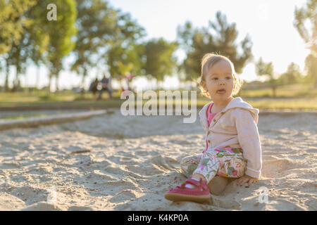 Quindici mesi Baby girl giocando nel sandbox il tramonto Foto Stock