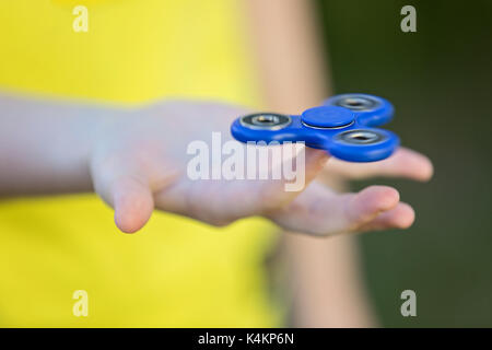 La mano della bambina tenendo una filatura agitano: spinner in mano li filatura sul suo dito indice Foto Stock