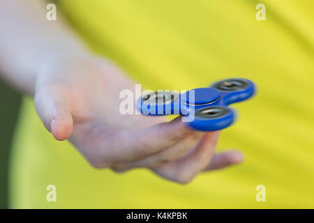 La mano della ragazza che tiene una pinnetta che gira nella sua mano, la gira sul suo dito indice Foto Stock