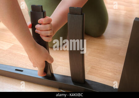 La donna si monta sedia da pranzo dei pezzi di legno nero. Foto Stock