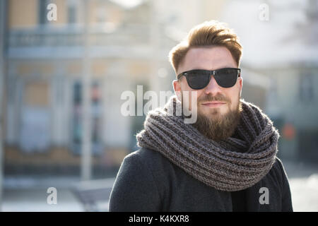 Ritratto di un uomo barbuto in abbigliamento invernale in piedi in città Foto Stock