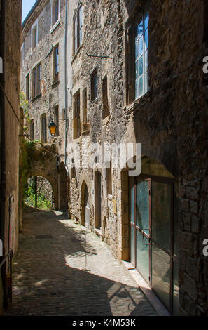 Un tipico vicolo stretto nella città di Montelimar in Francia con alti edifici in pietra e portali con ombre scure Foto Stock