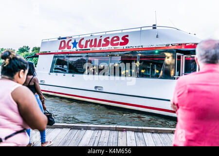 Washington DC, Stati Uniti d'America - 4 Agosto 2017: le persone in piedi in Georgetown parco sul lungofiume in serata con il fiume Potomac e DC barca Crociere Foto Stock