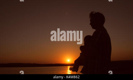 Padre tiene il Bambino fra le braccia al tramonto. slow motion. Foto Stock