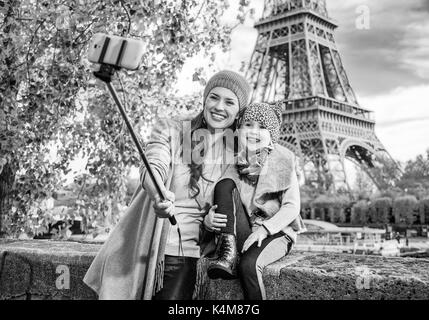 Fughe d'autunno a Parigi con la famiglia. felice la madre e il bambino i turisti sul terrapieno vicino alla Torre Eiffel a Parigi, Francia tenendo selfie utilizzando selfie stic Foto Stock